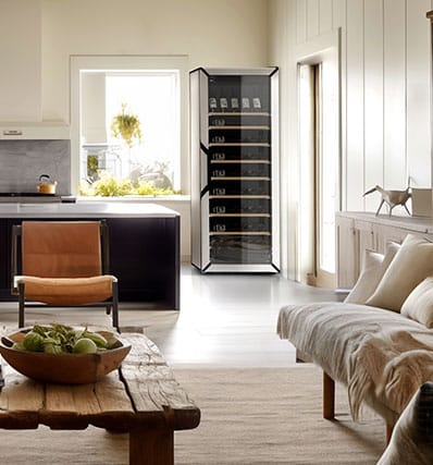 Un canapé blanc et un fauteuil marron devant une cuisine noire.